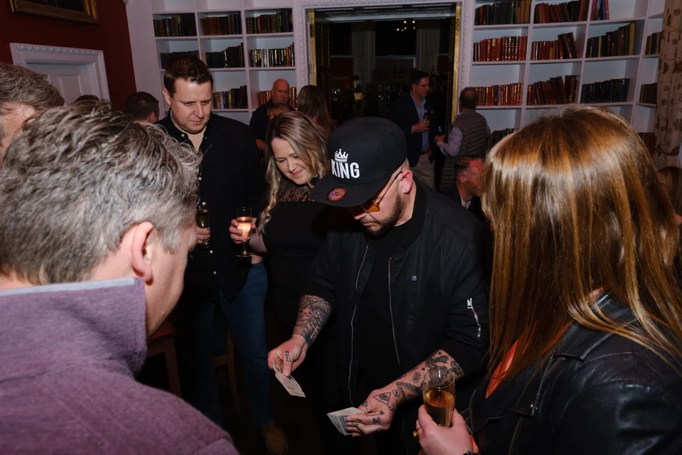 Phil Pearson performing close-up magic surrounded by guests