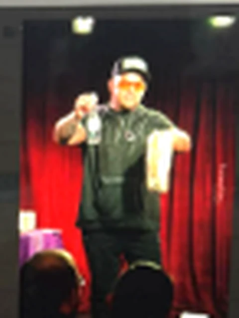 Phil Pearson performing visual magic on stage in front of red curtains